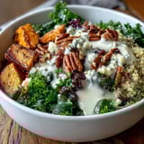 A bright drizzle of lemon tahini dressing adds zest, with pecans, cranberries, and blue cheese crumbles.