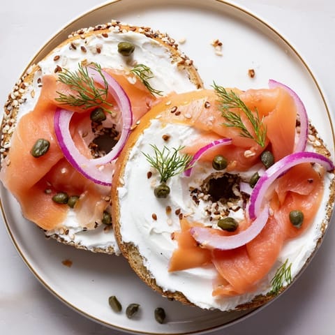 Warm bagel with cream cheese topped with smoked salmon, fresh dill, and red onion for a savory bite.