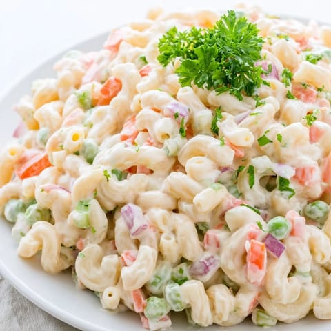 Fresh, creamy Macaroni Salad with diced red bell pepper, crisp celery, and chopped parsley in a chilled serving bowl.