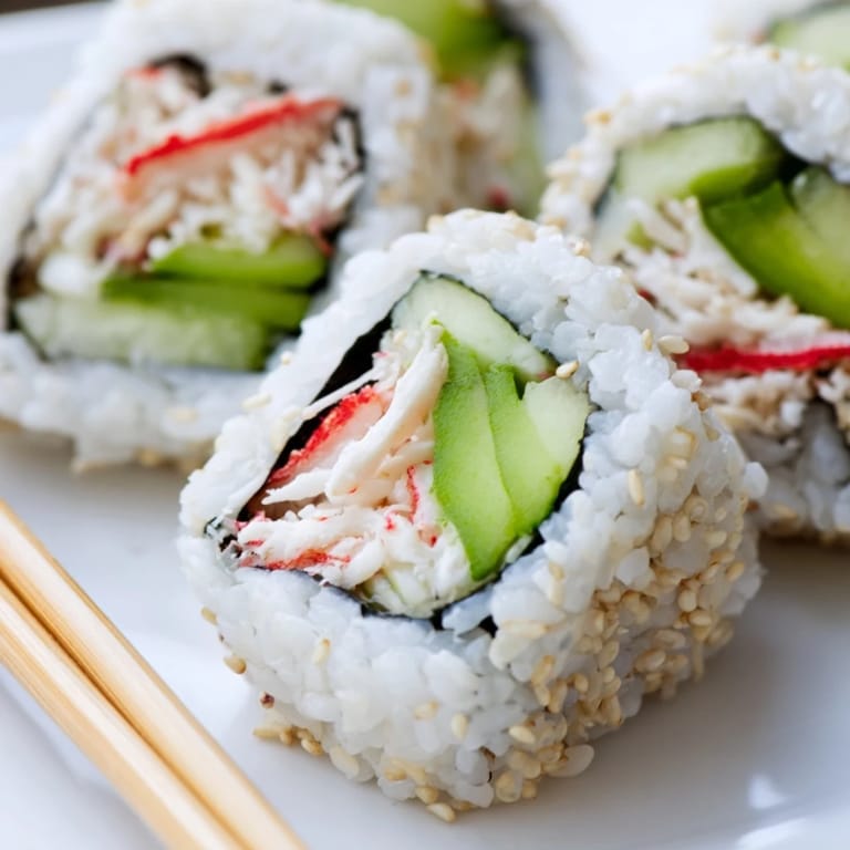 Homemade California Roll ingredients arranged on a wooden board: ripe avocado, shredded crab, and nori sheets, perfect for a medium-difficulty sushi recipe.