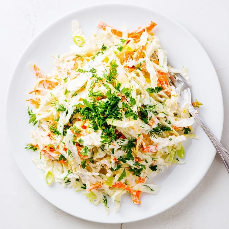 Easy homemade Coleslaw with Apple tossed with crunchy vegetables, creamy dressing, and parsley garnish, ready to serve at a summer barbecue or picnic.