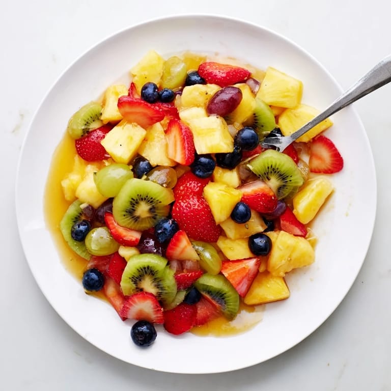 Healthy Fruit Salad, ideal for summer potlucks, glistening with honey-orange syrup and fresh mint leaves.