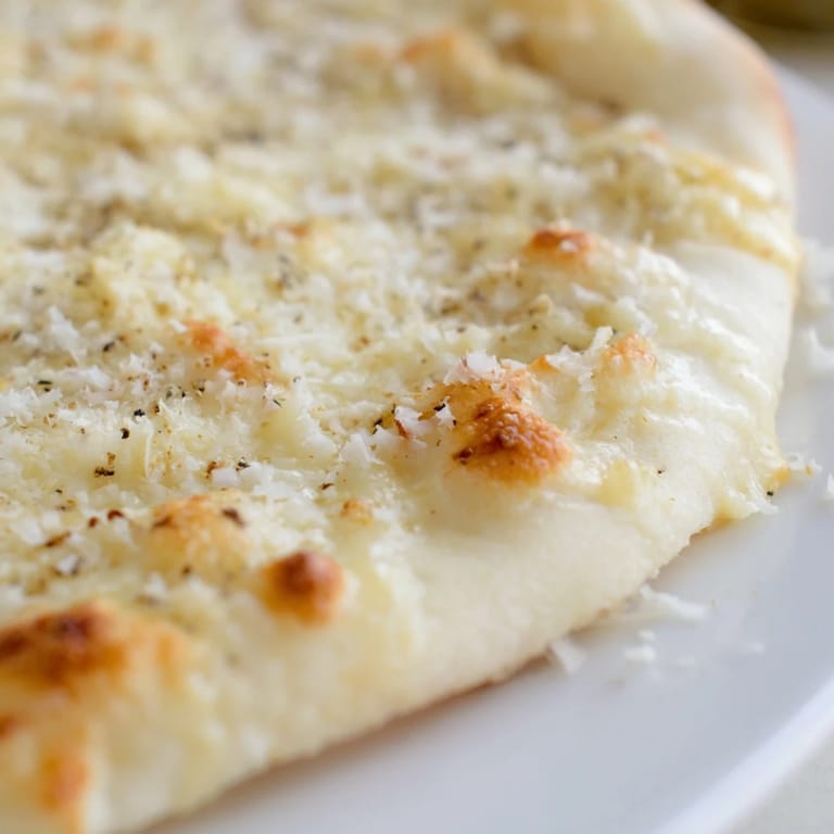 A bubbling Creamy Garlic White Pizza slice on a wooden board, showcasing velvety garlic cream sauce under cheese.