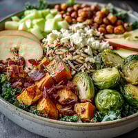 Vibrant Fall Harvest Bowl topped with crumbled feta and toasted almonds over roasted sweet potatoes.