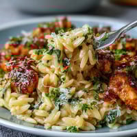 Lemon orzo with chicken and spinach in a creamy skillet, garnished with Parmesan and fresh parsley.