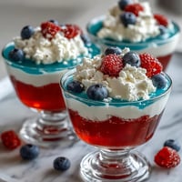 Vibrant red, white, and blue Jello cups layered in clear glasses, perfect for patriotic parties and summer celebrations.